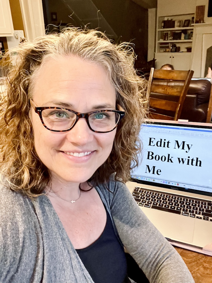 Janyre, an award-winning editor and best-selling author sitting with her computer which reads "Edit My Book with Me."